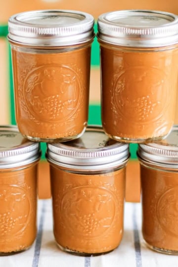 sweetened milk caramel in glass canning jars with lids stacked on a wood table